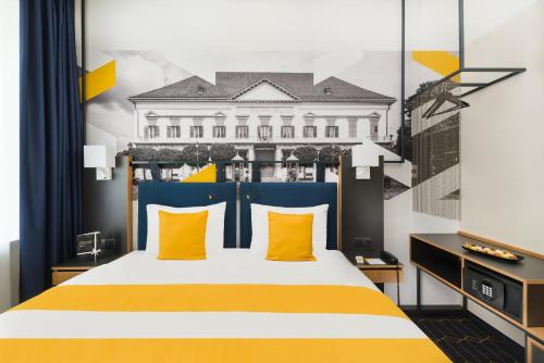 a bedroom with a large bed with yellow pillows at voco Budapest D8 by IHG in Budapest