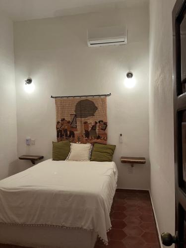 a bedroom with a white bed with a painting on the wall at Casa Lo de Linda in Lo de Marcos