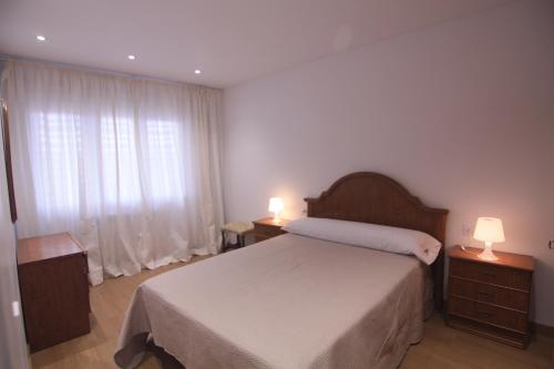 a bedroom with a bed and two lamps and a window at Fogar dos Americanos in Borneiro