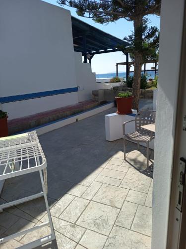 a patio with two chairs and a table and a tree at Syrtaki Studios in Kámpos