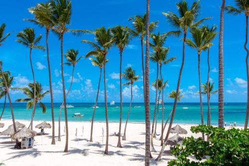 a group of palm trees on a beach with the ocean at FIESTA DEL CARIBE - LOS CORALES beach in Punta Cana