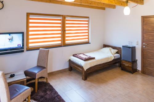 a bedroom with a bed and a tv and a chair at Motel Orhideja in Donji Vakuf
