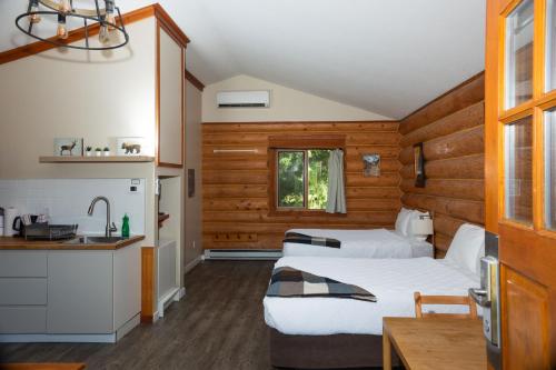 a hotel room with two beds and a kitchen at Glacier House Hotel & Resort in Revelstoke