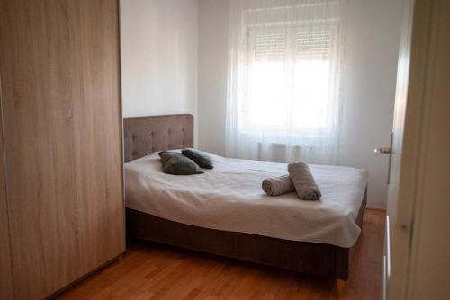 a bedroom with a bed with two pillows and a window at VukaNest apartman Jagodina in Jagodina