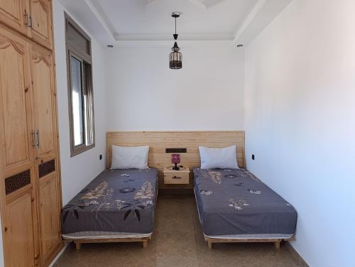 a bedroom with two beds and a nightstand at Appartements Hajar in Oualidia