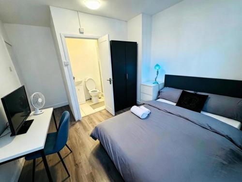 a bedroom with a bed and a desk and a bathroom at The Heath Haven- Morden 4 Bedroom House Near Station High Street, Free Parking WiFi in Goodmayes