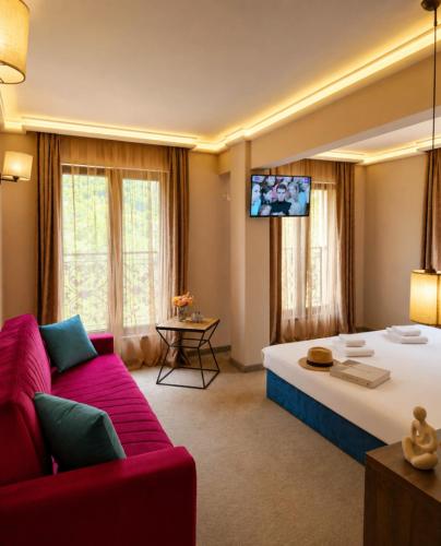 a large room with a large bed and a red couch at Вила АРБОРЕТУМ in Teteven
