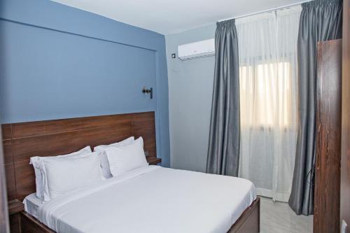 a bedroom with a large white bed and a window at Angel's hôtel in Douala
