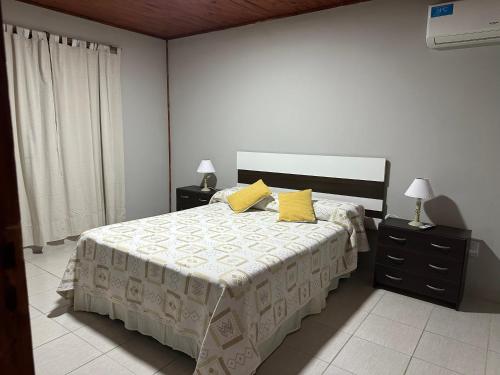 a bedroom with a bed with two yellow pillows at Cabañas Adorable Tranquilidad in Cavalango