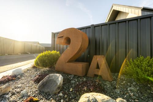 a large wooden sign in a yard next to a fence at Stay at 2A in Twizel