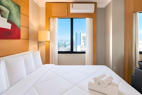 a bedroom with a white bed with two towels at Flat Moderno em Congonhas com sofá-cama 1113 in São Paulo