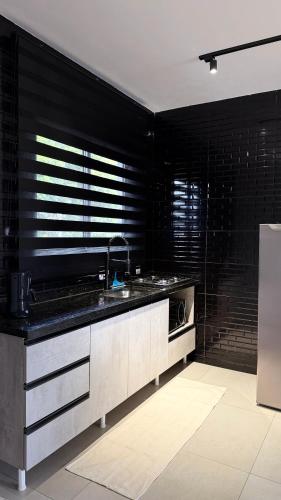 a kitchen with a sink and a black wall at Studios Carambeí in Carambeí