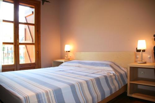 um quarto com uma cama com um cobertor listrado e uma janela em Apartamentos Cogulla em Benasque