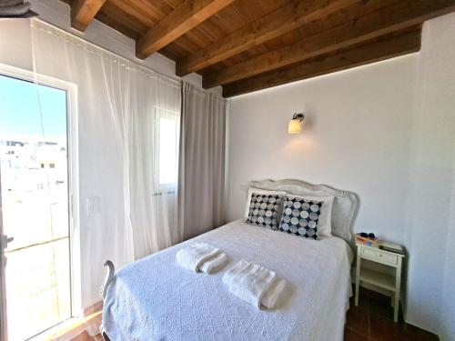 a bedroom with a white bed with a window at Olhão Barreta typical home ASM in Olhão