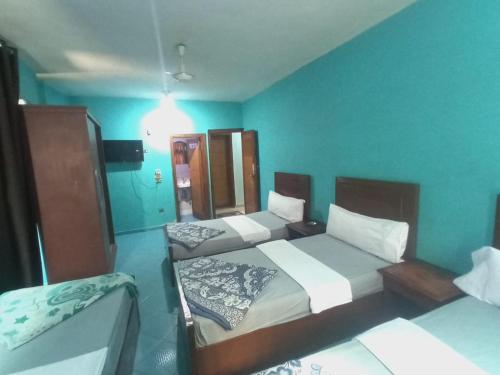 two beds in a room with blue walls at Aswan City Center Guest House in Aswan
