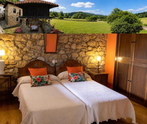 a bedroom with two beds and a stone wall at La Casina de Celorio in Celorio