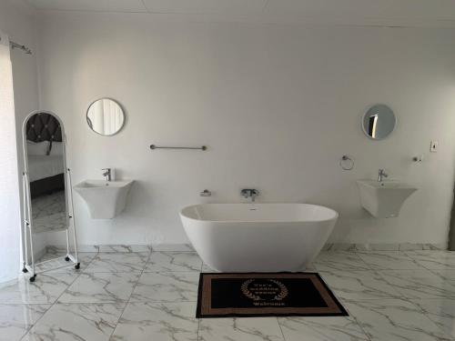a white bathroom with a tub and two sinks at Veesboutiquehotel in eMalahleni