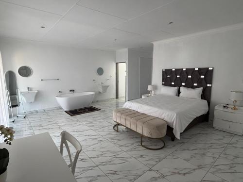 a white bedroom with a bed and a tub and a sink at Veesboutiquehotel in eMalahleni