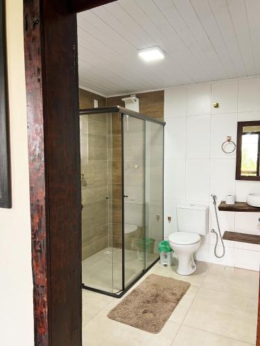 a bathroom with a glass shower and a toilet at Chalés do Chá in Lavras Novas