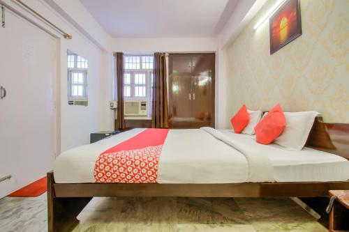 a bedroom with a large bed with red and white pillows at Hotel O Kamini in Patna
