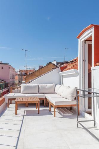 a patio with couches and tables on a roof at Flores 21 Apartments Príncipe Real in Bicas