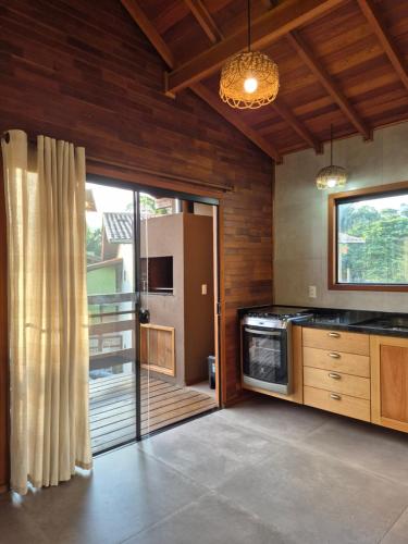a kitchen with wooden walls and a sliding glass door at Charme e conforto - surf pertinho de casa in Garopaba