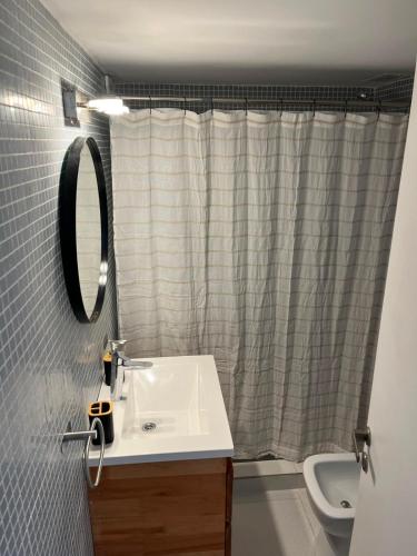 a bathroom with a sink and a mirror and a toilet at Torre Parque Apartamento in Morón