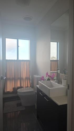 a bathroom with a sink and a toilet and windows at Sunset in Pakenham in Pakenham