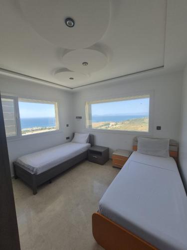 a bedroom with two beds and two windows at Villa mnar 3 chambre en haut in Tangier