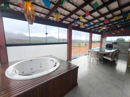 a large room with a bath tub and a table at Chácara Sol e Lua dos três Morros in Piatã