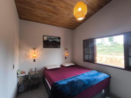 a small bedroom with a bed and a window at Chácara Sol e Lua dos três Morros in Piatã