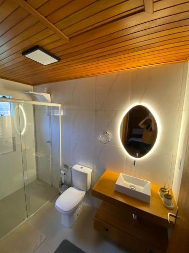 a bathroom with a toilet and a sink and a mirror at Sítio Brisa da Serra Conforto e Tranquilidade in Lauro Müller