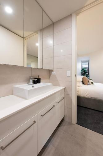 a white bathroom with a sink and a bed at Bentleigh & Beyond Your Melbourne Getaway in Melbourne