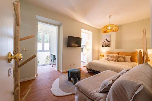 a bedroom with two beds and a couch and a tv at Flores 21 Apartments Príncipe Real in Bicas