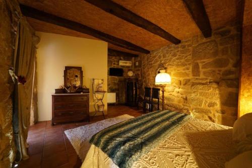 a bedroom with a bed and a stone wall at Quinta da Eira do Prado in Carvalho