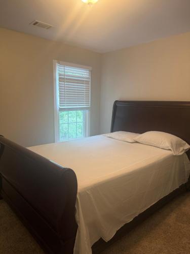a bedroom with a large white bed with a window at Stone Homes in Lawrenceville
