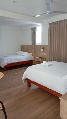 a hotel room with two beds and a table at Hotel San Cosme in Camaná