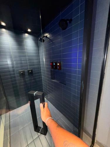 a person taking a picture of a blue tiled shower at Khalifa Experience Motel in Itumbiara