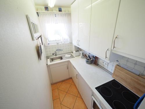 a small kitchen with white cabinets and a sink at Appartement-152 in Westerland