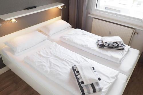 two beds with white sheets and a bag on them at Appartement-155 in Westerland