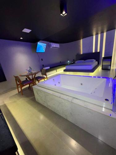a large bath tub in a room with a bed at Khalifa Experience Motel in Itumbiara