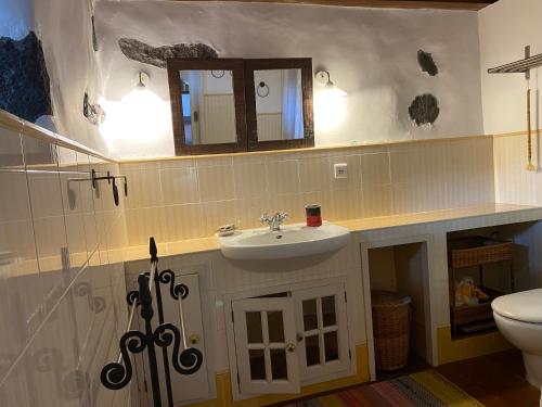 a bathroom with a sink and a toilet and a mirror at Casa dos Santos Historic Azorean Estate in Horta