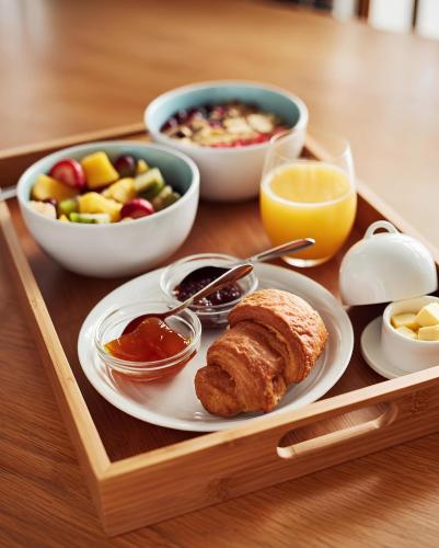 a tray of food with a plate of bread and fruit at Maison De Omashi in Kigali