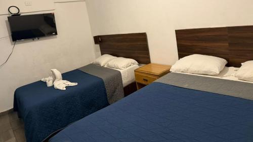 a hotel room with two beds and a flat screen tv at Hotel Vahuma in Monterrey