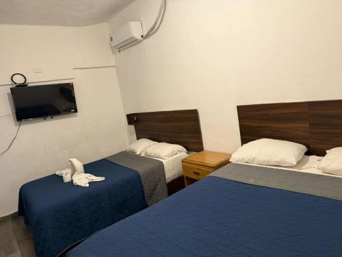 a hotel room with two beds and a flat screen tv at Hotel Vahuma in Monterrey