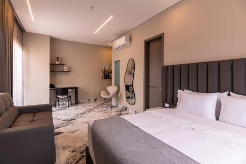a bedroom with a bed and a couch and a desk at Hotel Colores Estadio in Medellín