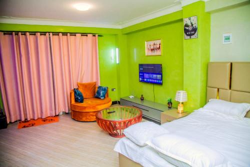 a bedroom with green walls and a bed and a chair at Blaize Affaire Apartments in Kampala