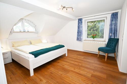 a white bedroom with a bed and a blue chair at Villa-Magnolia-H in Hohwacht
