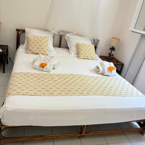 a large bed with white sheets and pillows at La Siguine in Gourbeyre