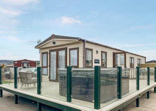 a tiny house on a dock with a deck at Whitehouse Holiday Park in Abergele